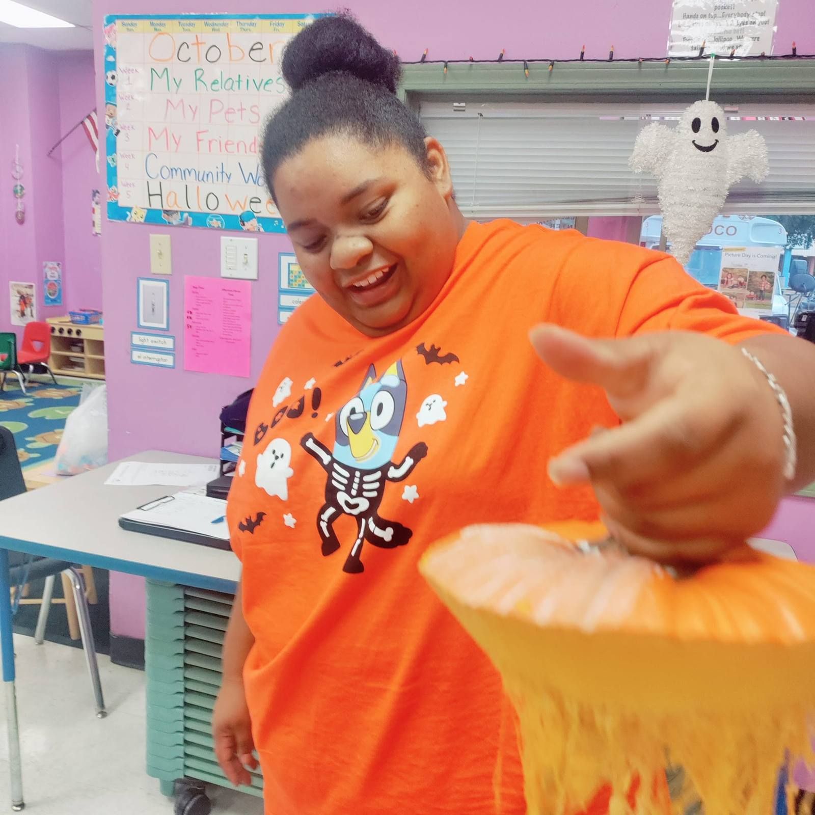 A Kidco teacher laughing while handing out Halloween treats